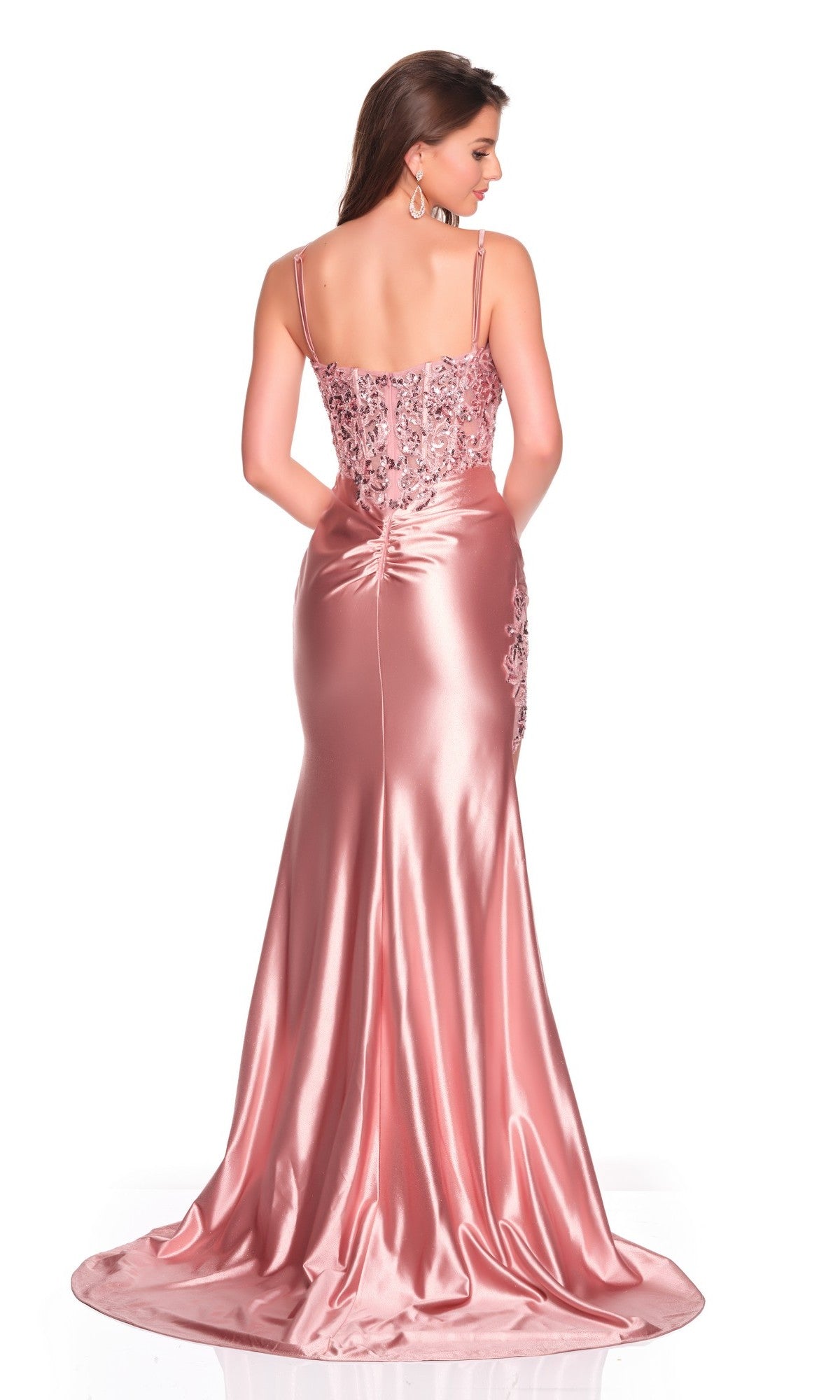 A woman stands facing away in the Dave and Johnny 12601 long prom dress, featuring a floor-length pink satin sheath skirt and floral lace detailing on the back.